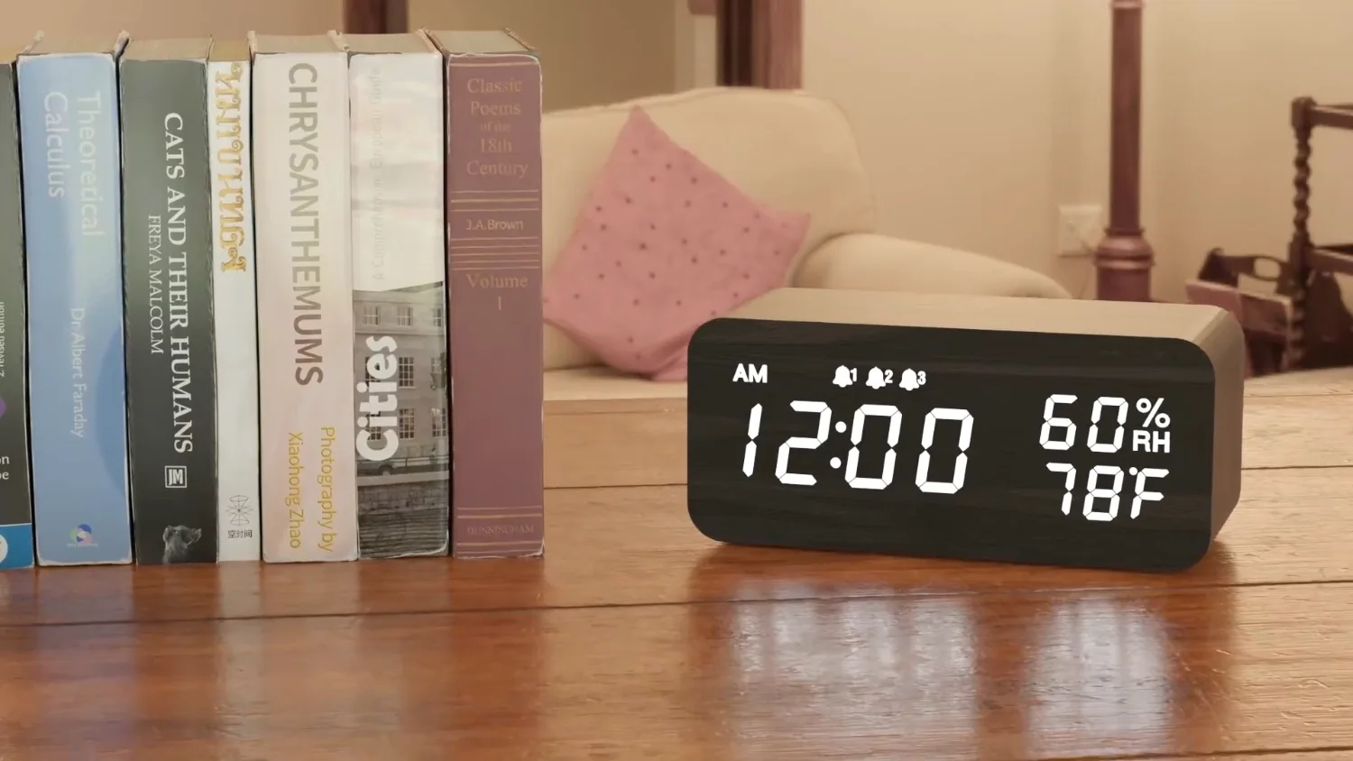 A JALL wooden alarm clock on a shelf between books, digits lit white