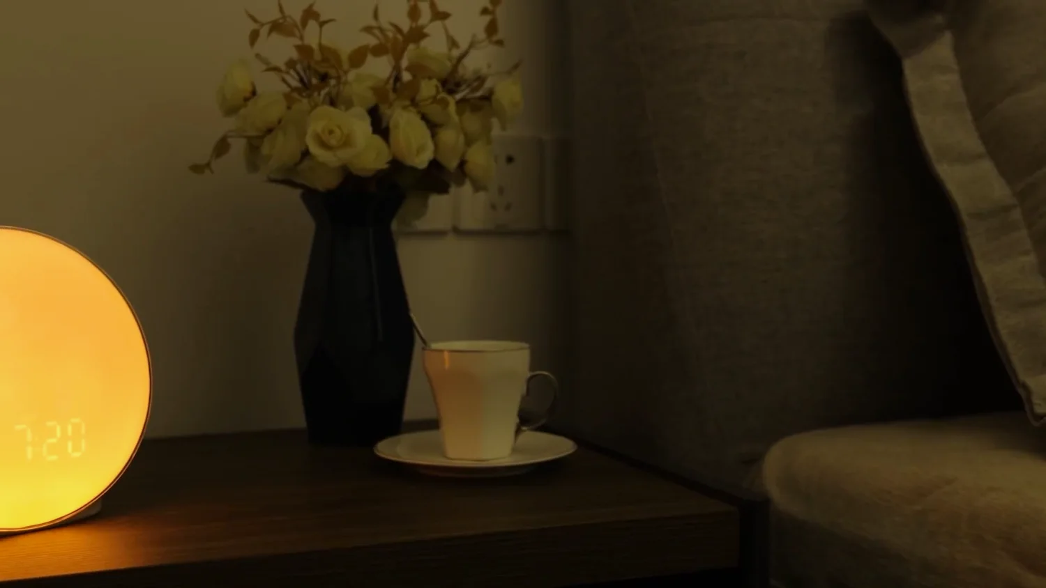 A JALL sunrise alarm clock lit at night on a bedside table